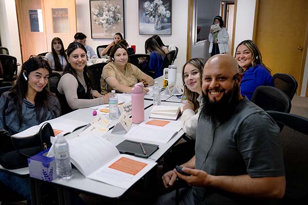 group of people, some with headsets, sitting around a table and smiling